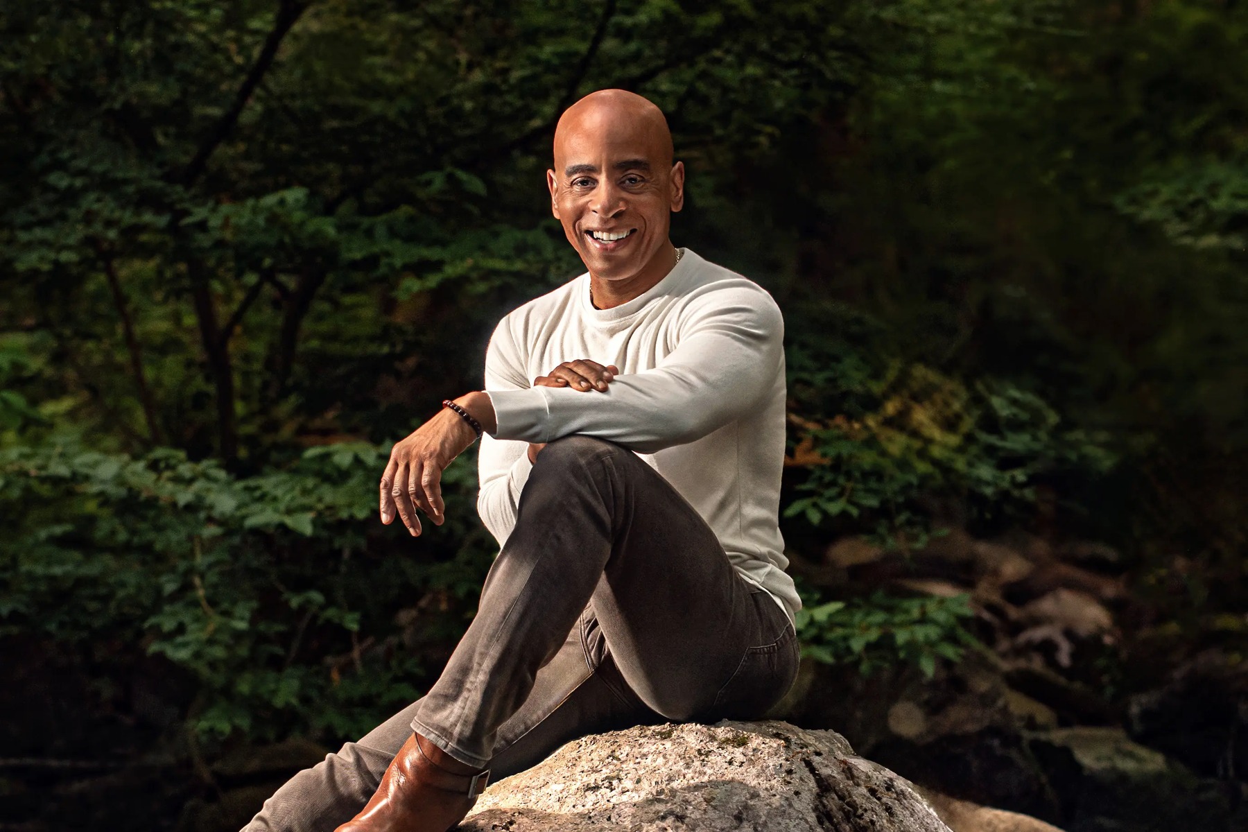 Terry Henry, online dating coach and founder of Dialed In Dating, sitting on a rock in a forest